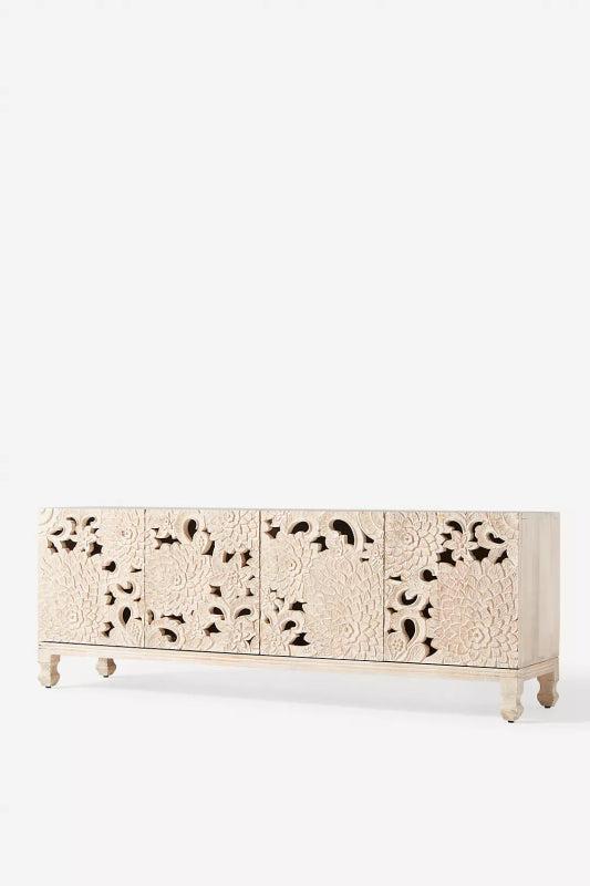 Anthropology Openwork Lotus Buffet in wood, shown in a three-quarter room view with carved door panels and low wooden legs.