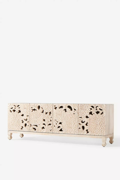 Anthropology Openwork Lotus Buffet in wood, shown in a three-quarter room view with carved door panels and low wooden legs.