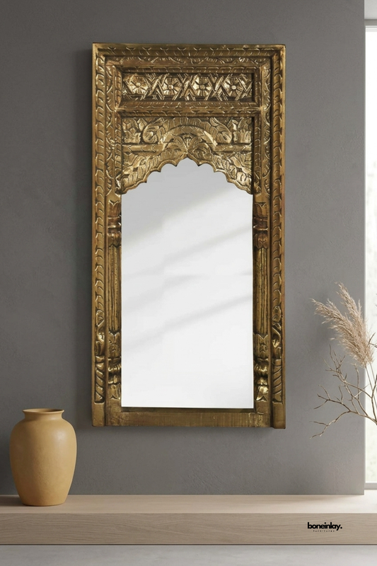 Antique gold carved wood wall mirror featuring an ornate arched silhouette with floral and geometric detailing. Rich gilded finish and traditional temple-inspired carving add dramatic vintage character. Styled above a wood console with a mustard ceramic vase and dried pampas grass. A striking statement mirror for entryways and eclectic interiors.