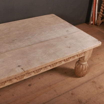 Rectangular wood occasional table with a pale, lightly marked top and carved edge, viewed from an elevated corner angle.