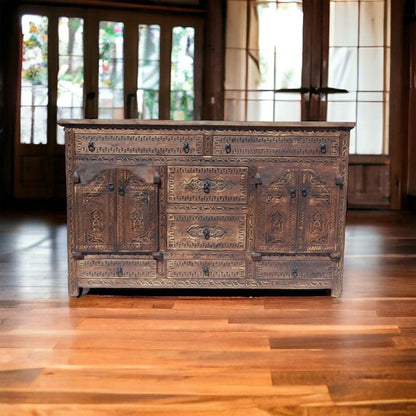 Rectangular wooden storage cabinet in rustic carved timber, styled in entryway on wood flooring before glazed doors.