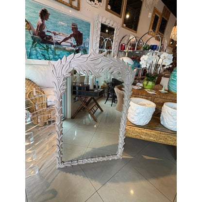 Regency acanthus looking glass in rustic carved wood, front view reflecting a dark tray table beneath the leafy crest.