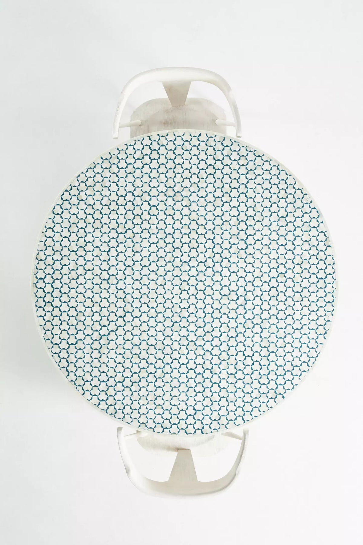 Overhead view of round teal bone inlay dining table showing full geometric surface pattern with white chairs around it