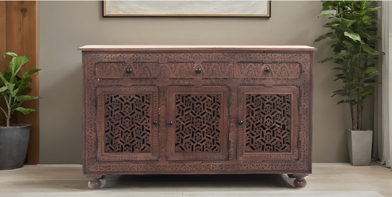 Rustic Jali door credenza in carved wood, styled in entryway beneath framed artwork with potted plants on either side.