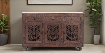 Rustic Jali door credenza in carved wood, styled in entryway beneath framed artwork with potted plants on either side.