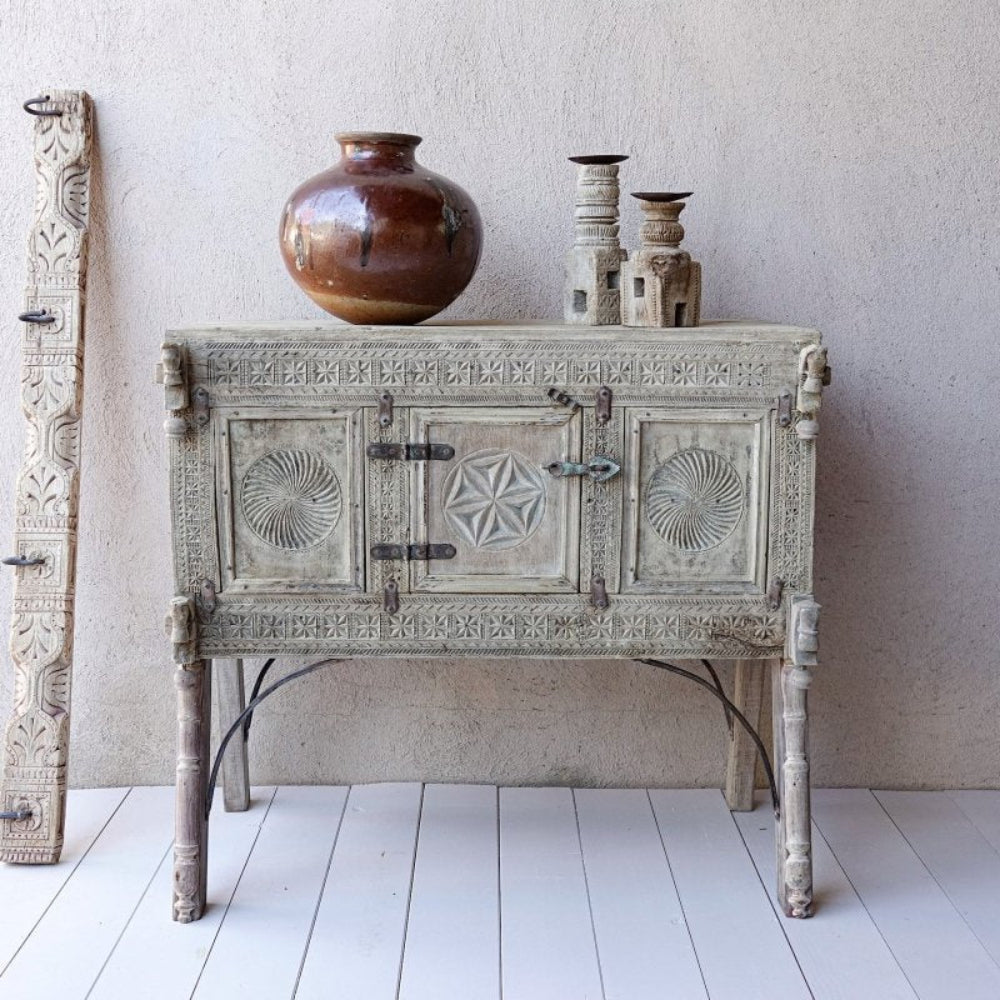 Rustic wood hope chest in a pale weathered finish, front view showing circular carvings, a star door and tall legs.