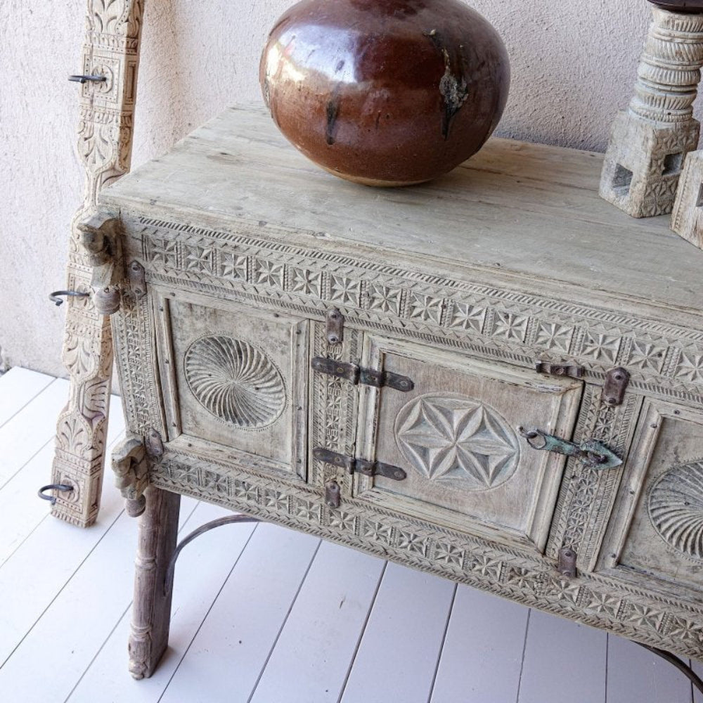 Rustic wooden blanket chest in a pale neutral finish, top view showing a pottery vase above the star-carved front.