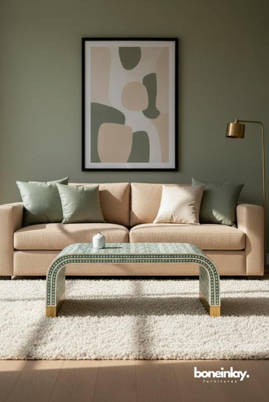 Sage green and white geometric bone inlay waterfall coffee table with U-shaped silhouette and gold brass feet, styled in a modern earth-toned living room with beige sofa and abstract wall art