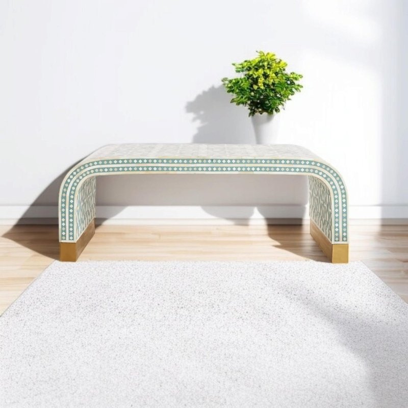 Sage green geometric bone inlay waterfall console table with U-shaped arch structure and brass feet base, placed on a light wood floor with a green potted plant in a minimalist white room