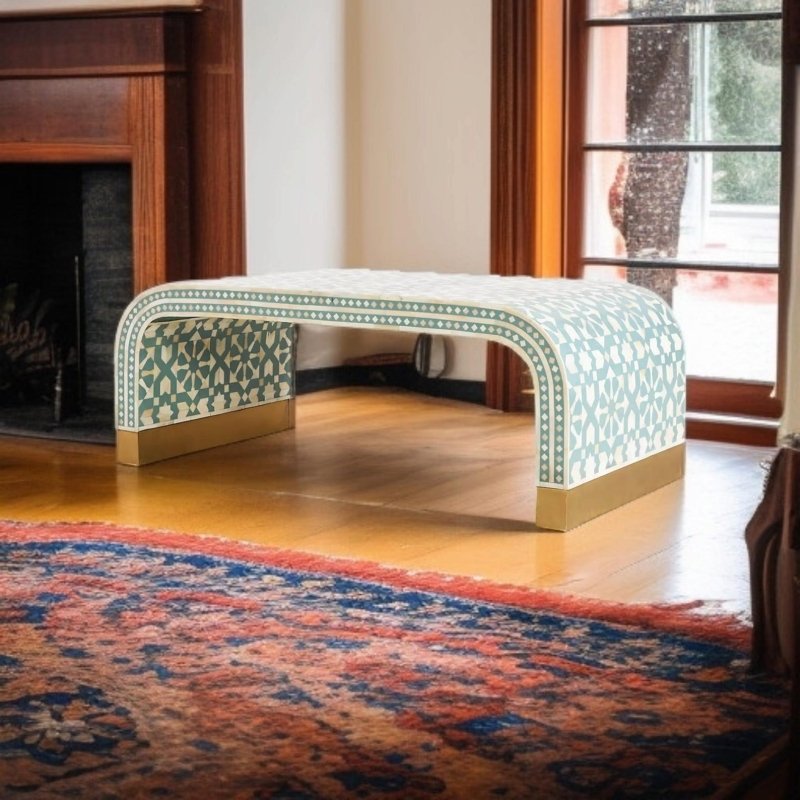 Sage green and white star-motif bone inlay waterfall lounge table with antique brass plinth base, placed on a vintage Persian rug beside a fireplace in a warm rustic interior