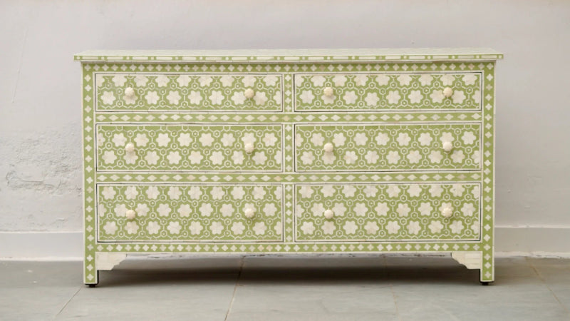 A wide sage green and white bone inlay dresser with six drawers featuring an intricate floral honeycomb pattern and hand-carved white knobs against a neutral background.