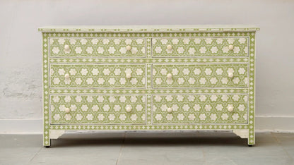 A wide sage green and white bone inlay dresser with six drawers featuring an intricate floral honeycomb pattern and hand-carved white knobs against a neutral background.