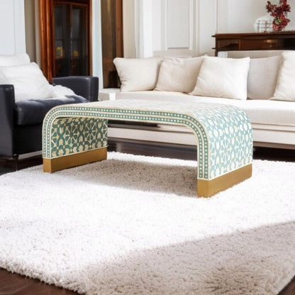 Sage green Moroccan geometric bone inlay waterfall coffee table with star-pattern inlay and brass plinth feet, placed on a white shag rug between a white sofa and dark leather chair in a classic living room