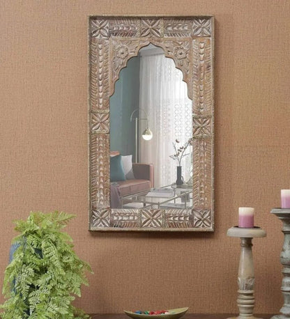 Scalloped arch accent mirror in weathered wood, styled in living room beside a fern and tall candle holders.