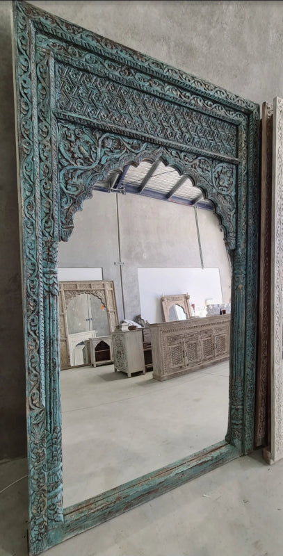 Scalloped arch standing mirror in rustic solid wood, front view with floral carvings around the reflective glass.