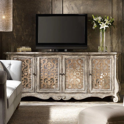 Against a dark wall, the carved white buffet faces forward with ornate doors and a lamp above in a styled room