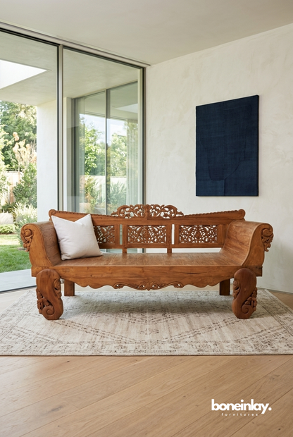 Large hand-carved solid daybed featuring an ornate floral fretwork backrest, rolled arms, and heavy scrolled legs in a warm natural finish.