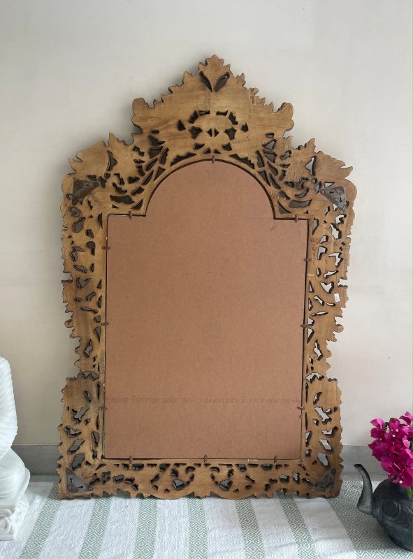 Solid wood looking glass, back view showing a brown backing panel, retaining clips and an ornate cutout border.