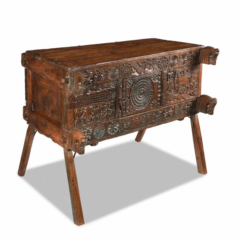 Solid wood trunk chest in natural walnut finish, angled front view showing the plain side and carved facade.