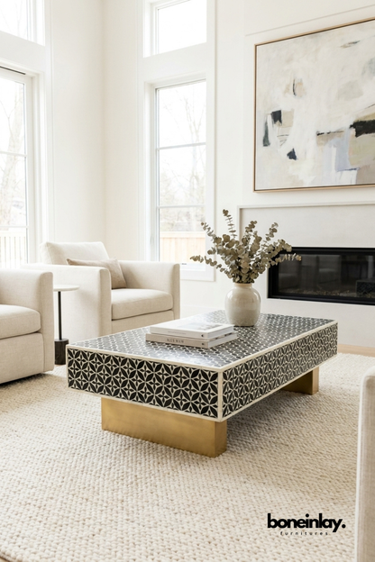 Stellar monochrome bone inlay coffee table with brass legs styled in a bright modern living room with white sofa and eucalyptus decor.