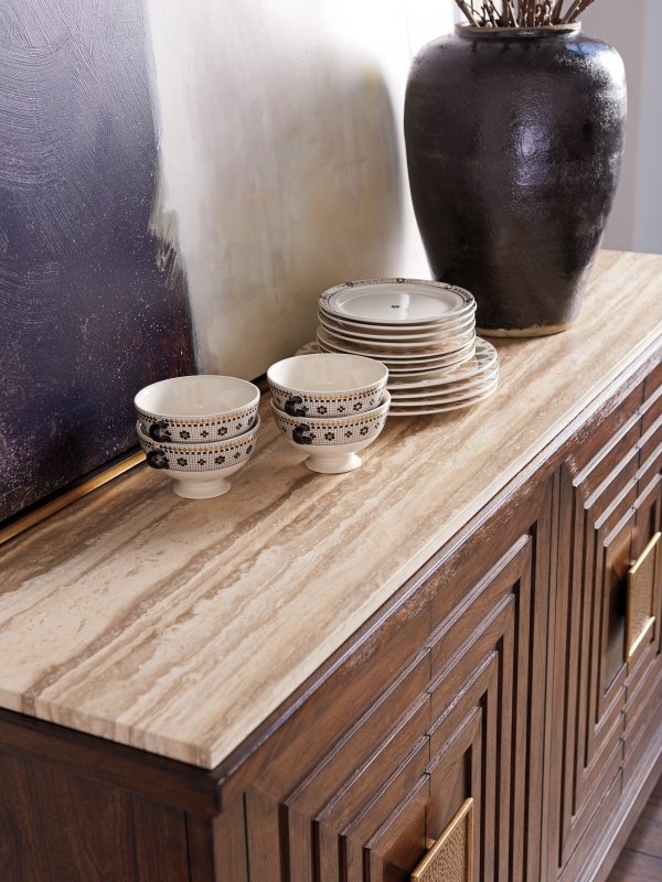 Stone-topped wood storage cabinet in walnut, edge detail view showing the veined stone overhang above carved doors.