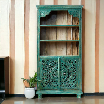 Tall hand-carved solid wood cabinet in distressed teal featuring a large mandala relief on the lower doors and three open natural wood shelves.