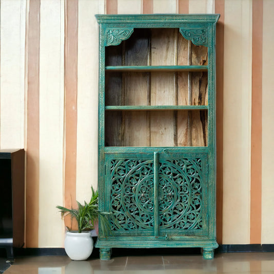 Tall hand-carved solid wood cabinet in distressed teal featuring a large mandala relief on the lower doors and three open natural wood shelves.
