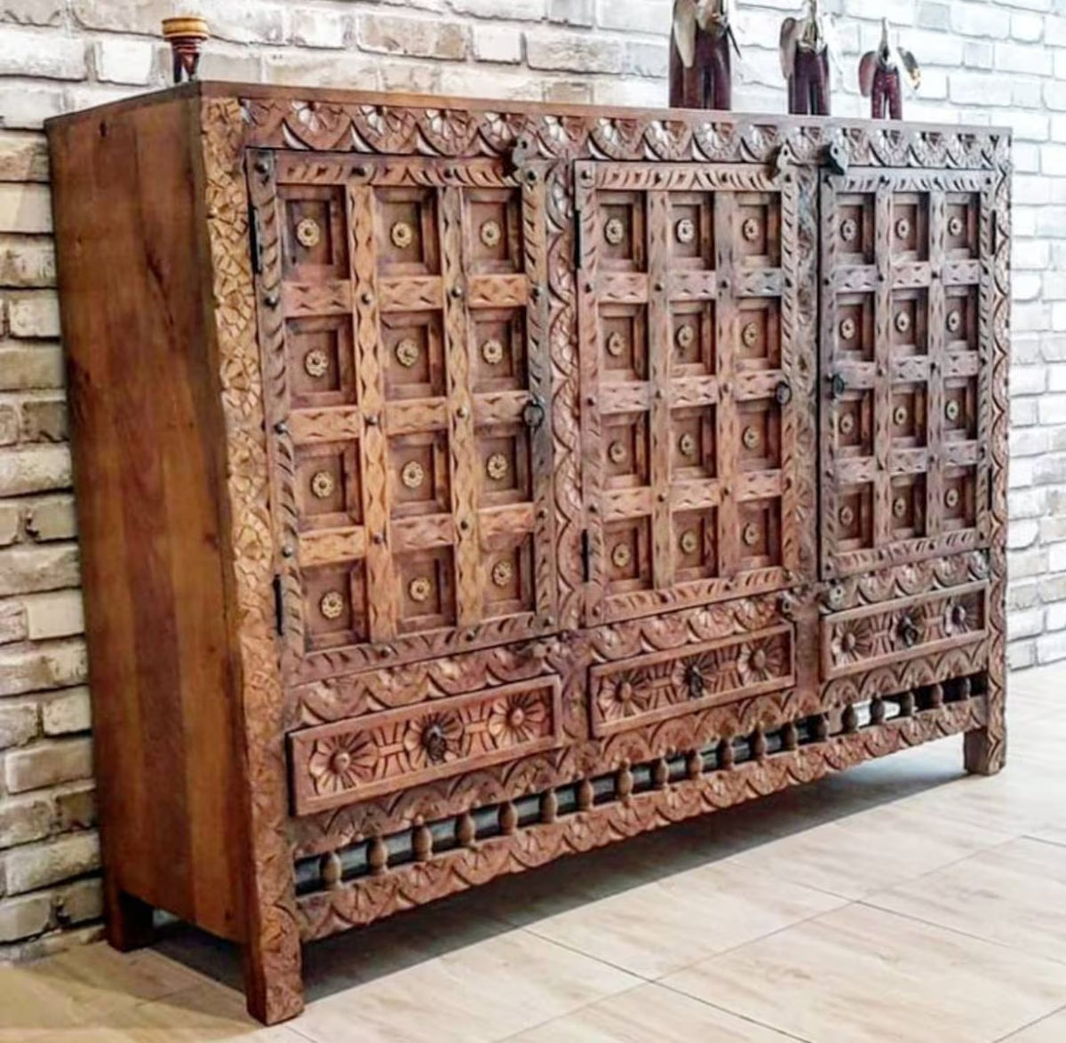 Three door Damchiya server in rustic solid wood, front view angled from the left with carved panels and ring pulls.