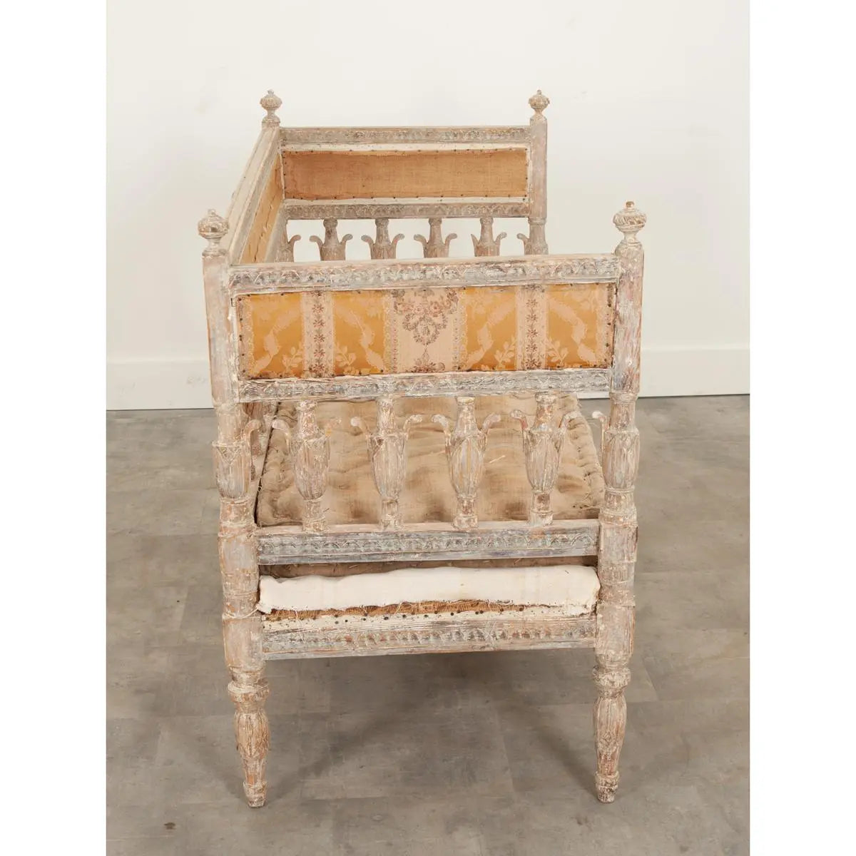 Traditional accent bench in a light finish, side profile view showing its upholstered seat, back rail, and legs.