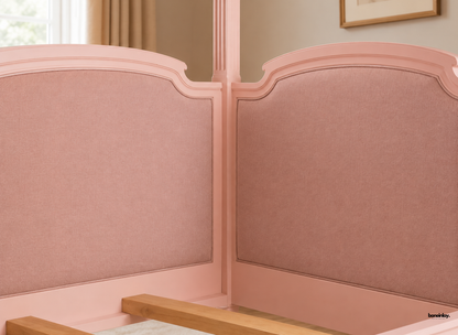 Close-up view of a handmade pink wooden canopy day bed showcasing finely upholstered curved headboard panels and fluted corner posts. This romantic artisan bed combines soft textured upholstery with exquisite craftsmanship for a chic bedroom aesthetic.