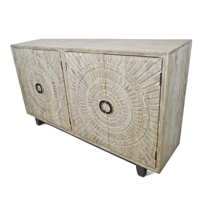 Washed medallion cabinet with carved doors and short feet, viewed from a front corner against white.