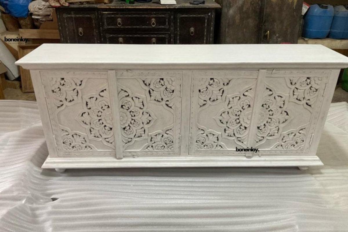 White carved wood server in a front view, showing its floral cabinet doors beneath a broad, flat top.