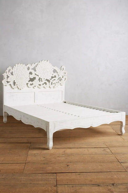 Front view of a hand-carved lotus platform bed in whitewash mango wood, styled with white bedding in a warm neutral bedroom.