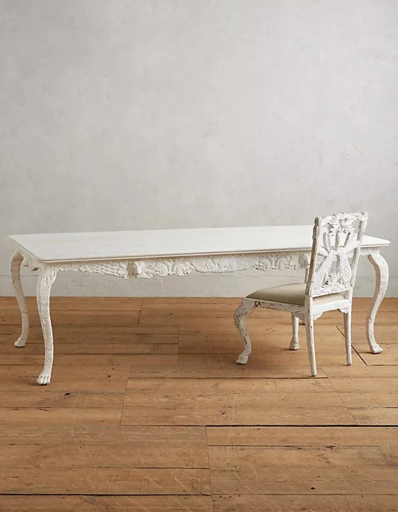 The same hand-carved wooden dining table and chair set presented in a distressed white finish for a French country or shabby-chic aesthetic.