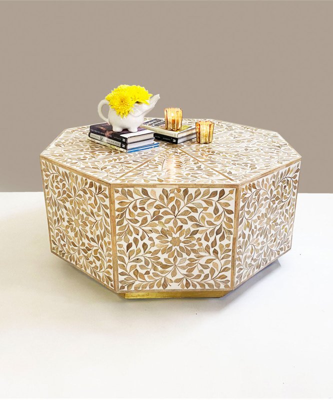 Wooden octagonal bone inlay coffee table with all-over floral leaf mosaic pattern in beige and gold tones, styled with yellow flowers and gold candle holders on neutral background