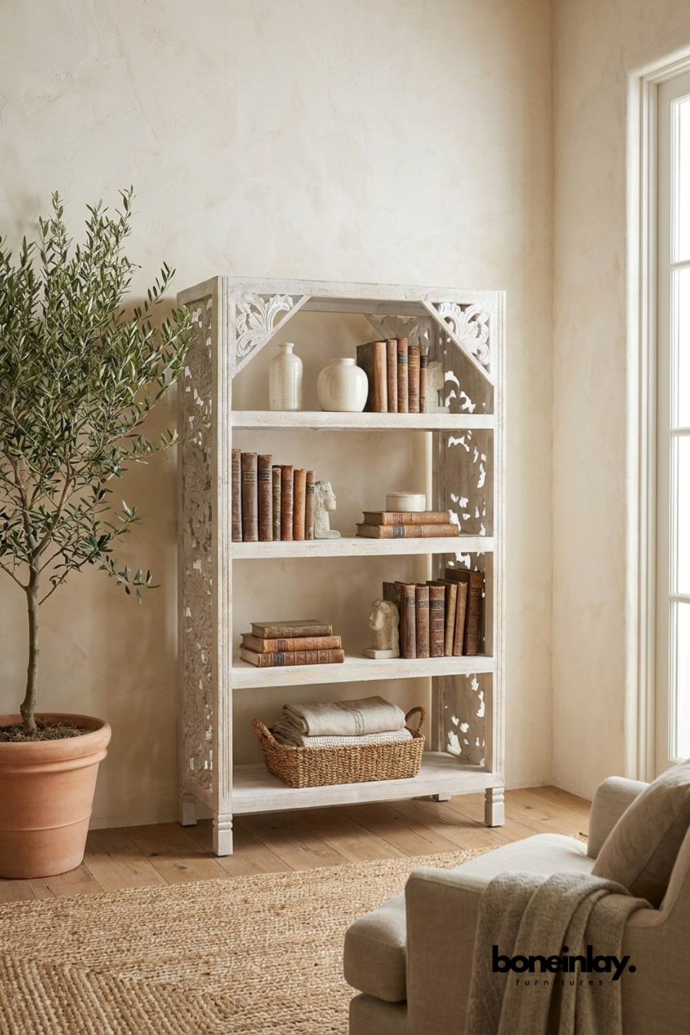 Whitewashed carved wood bookshelf with four open display shelves.
Corner brackets feature detailed carved floral fretwork detailing.
Distressed white finish reveals natural wood grain beneath.
Styled with stacked antique books and a woven storage basket.