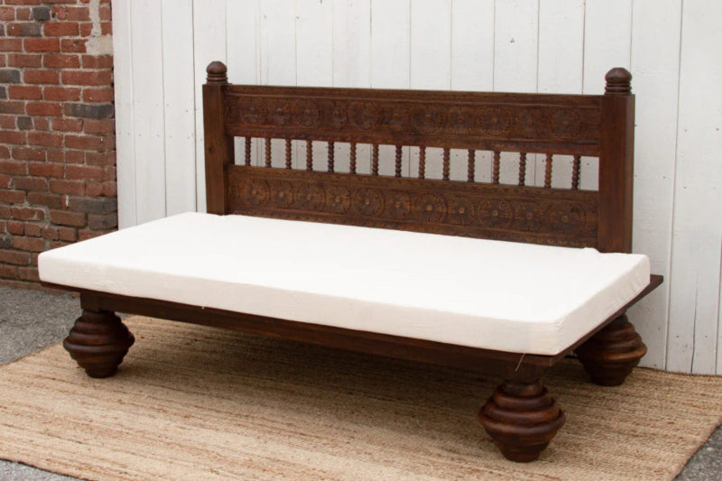 Wooden sofa daybed with a slatted back and white seat cushion, shown in side profile against a plain wall.