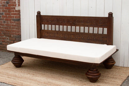 Wooden sofa daybed with a slatted back and white seat cushion, shown in side profile against a plain wall.