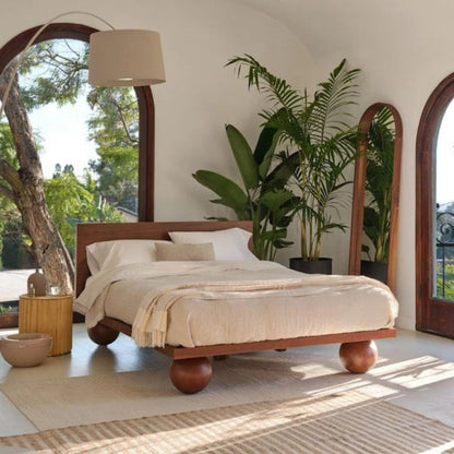 Agneta modern solid wood platform bed frame featuring four thick sculptural round sphere ball feet and a sleek low-profile headboard in a bright bedroom setting.