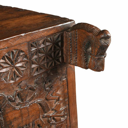 Sculpted corner trunk chest in natural solid wood, corner detail view of the projecting carving and patterned front.
