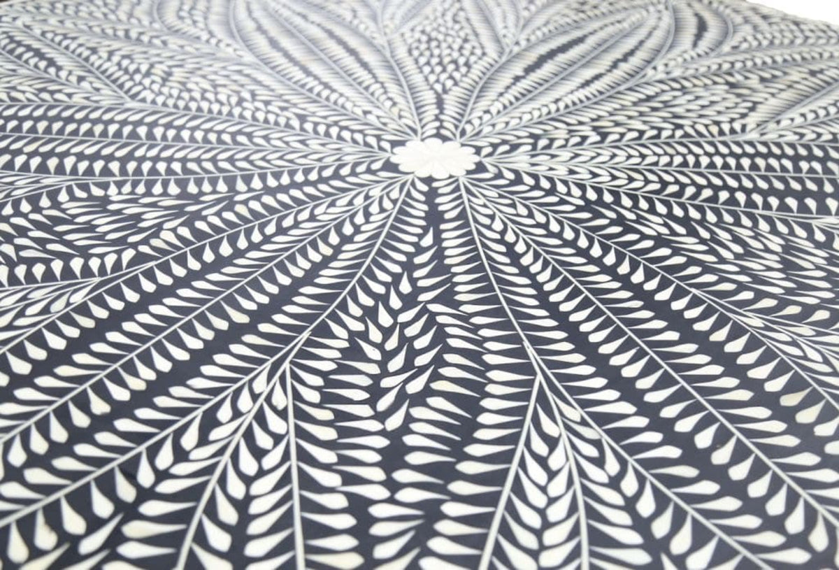 Close-up of ivory bone inlay leaves radiating from a floral center on the black dining tabletop.