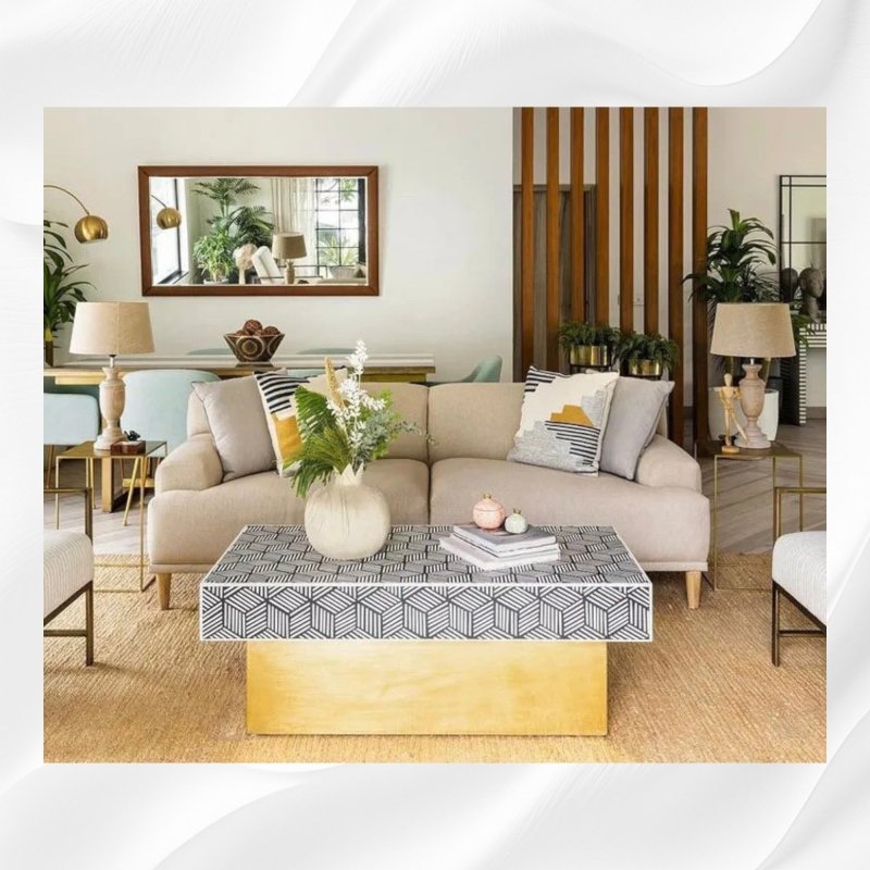 Front view of a rectangular black and white optical geometric bone inlay coffee table with a large gold pedestal base in a modern living room.