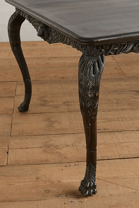 Black cabriole kitchen table in solid wood, close-up of leg showing its curved shape beneath the dark apron.