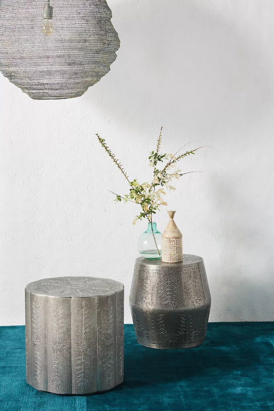 Handmade metal drum end table featuring a raised botanical pattern over a textured cross-hatched background.