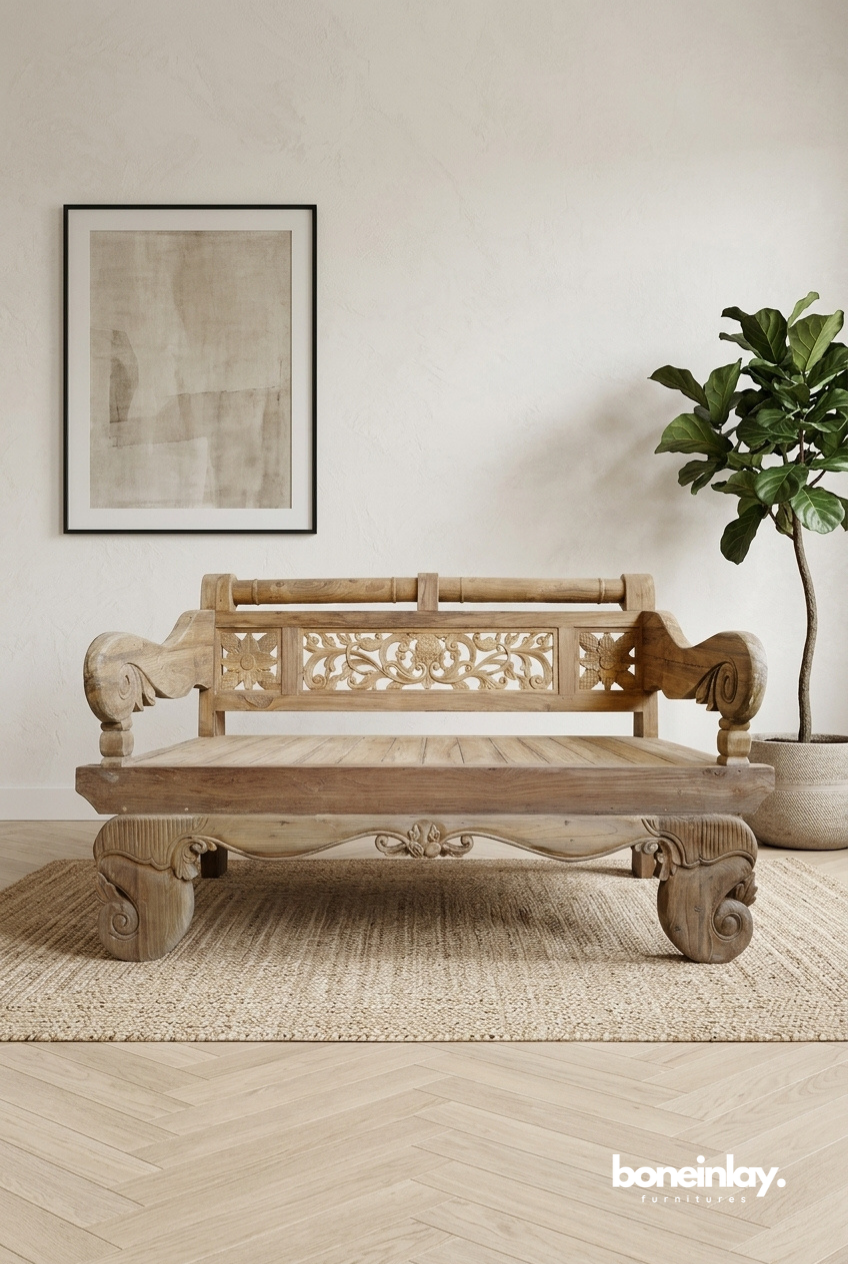 Front view of a wide, low-profile solid wood Javanese daybed bench in a natural finish, featuring a hand-carved floral backrest and large, heavy scrolled feet.