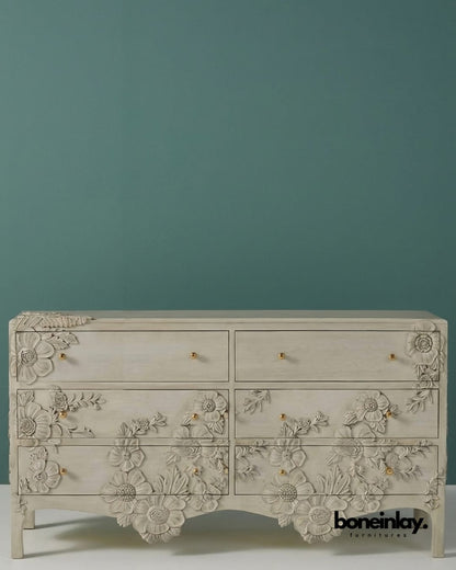 Enchantment dresser featuring hand-carved floral patterns in distressed white wood with gold-tone knobs.