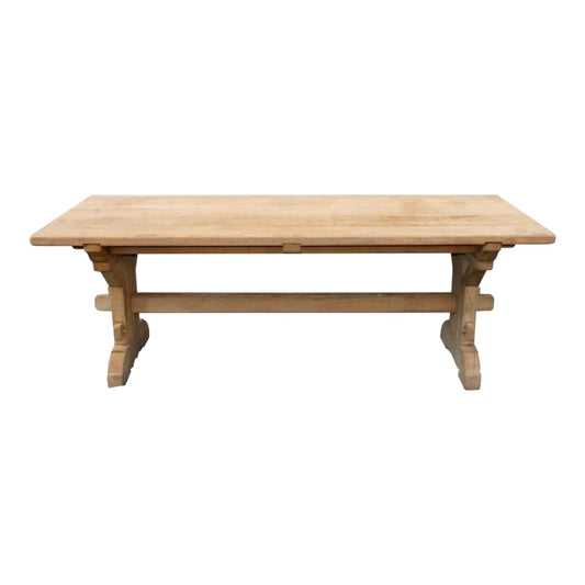 A luxury solid wood trestle dining table with a thick natural timber top and a handcrafted architectural support base.
