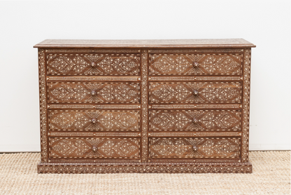 Floral wood inlay chest with eight closed drawers and a patterned plinth base, displayed on a woven rug.