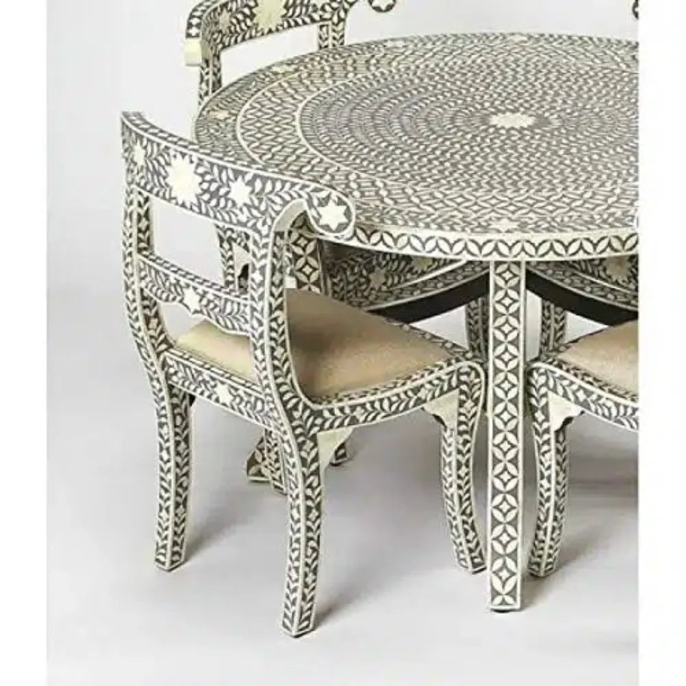  Detail of a gray bone inlay dining chair with an ivory floral backrest, cream upholstered seat, and matching round table.
