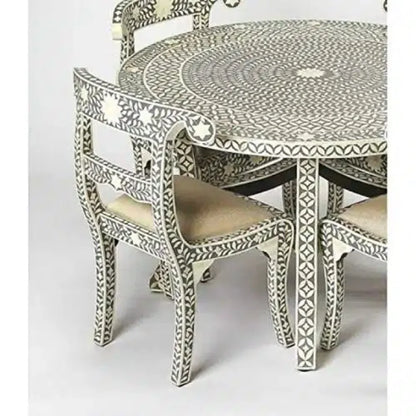  Detail of a gray bone inlay dining chair with an ivory floral backrest, cream upholstered seat, and matching round table.